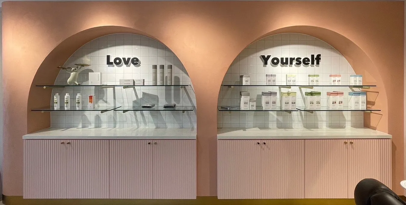 店内の Love Yourself アーチと製品ディスプレイ。落ち着いたピンク基調のインテリア